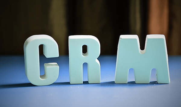 푸른 색 테이블 위에 우뚝 서 있는 'CRM'이라는 블록 모양