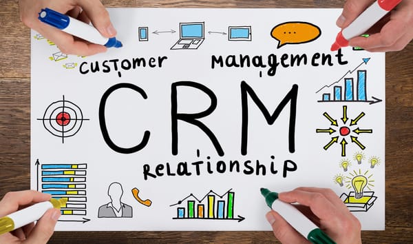 CRM 마케팅을 상징하는 그림이 프린트된 A4 용지에 여러 사람이 사인펜으로 마킹하는 모습